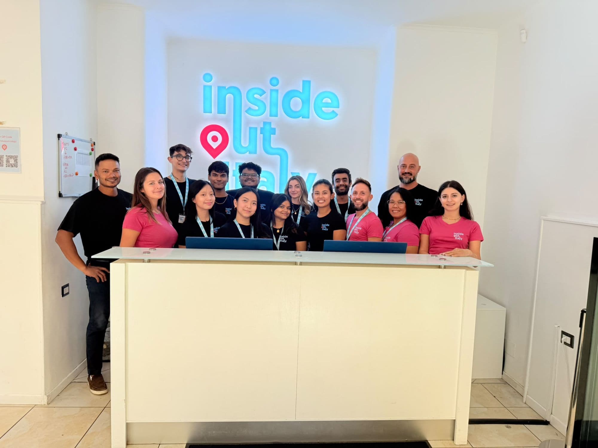 The Inside Out Italy team in branded T-shirts at the front desk, under the illuminated Inside Out Italy sign