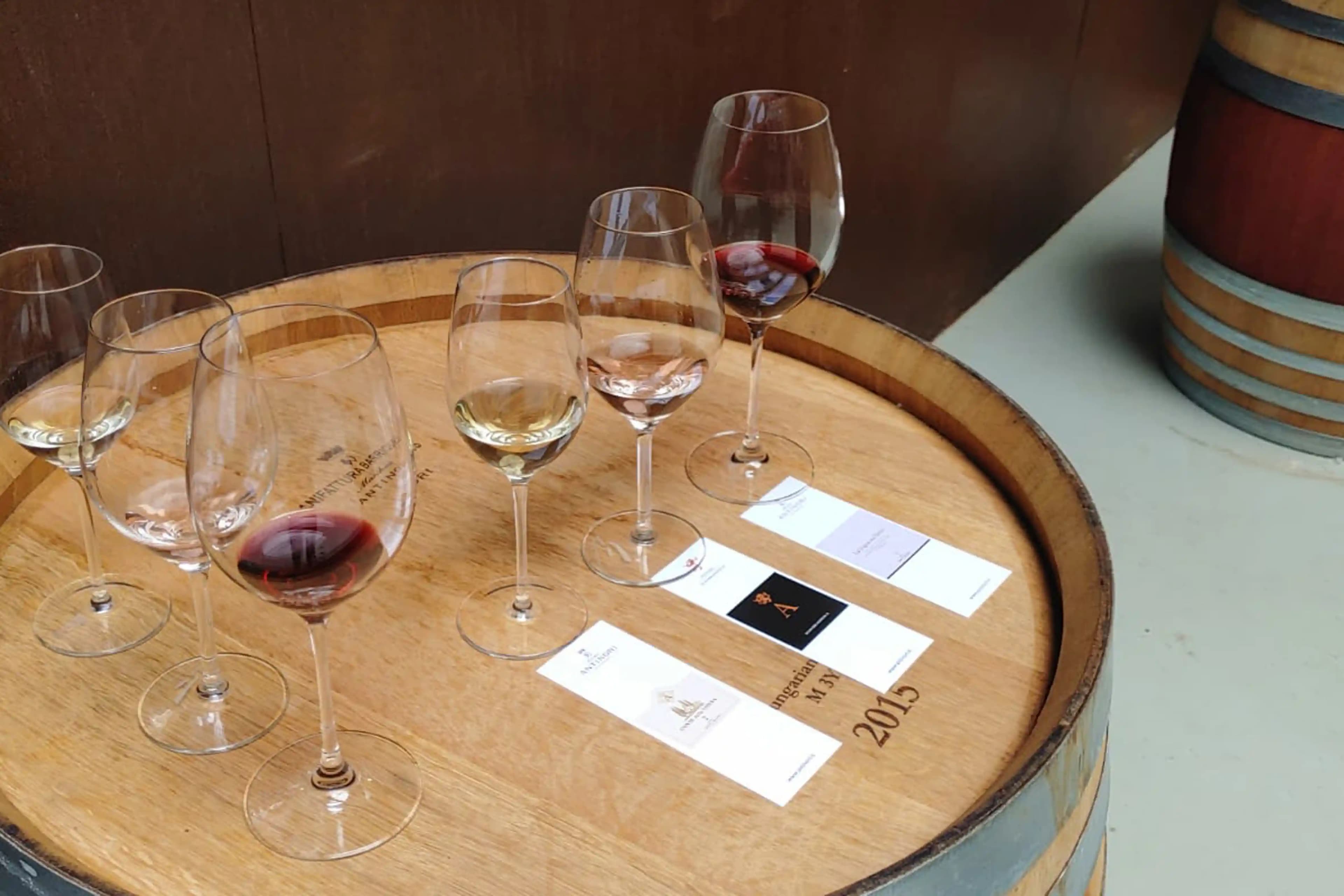 Wine tasting setup at Brolio Castle with red, white, and rosé wines served on a barrel with labeled cards